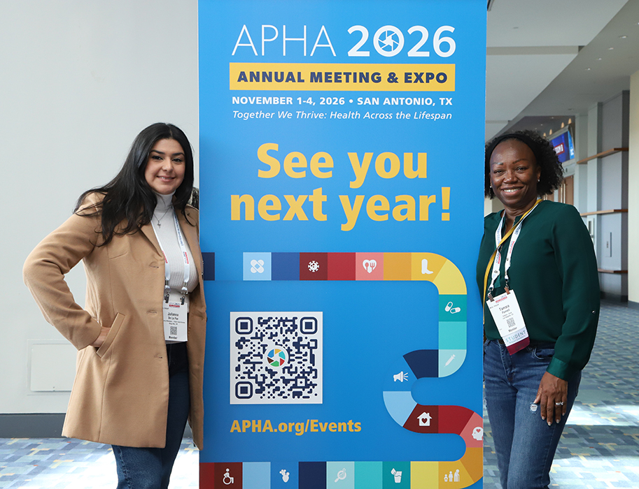 Two women pose on either side of a free-standing APHA banner that says "See you next year!"